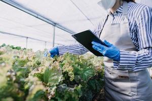 Futuristic businessman farms vegetables and crops using modern AI technology using mobile phones, temperature and humidity sensors, water tracking, climate control, holographic data data icons. photo