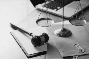 Justice and law concept.Male judge in a courtroom with the gavel, working with, computer and docking keyboard, eyeglasses, on table in morning light photo