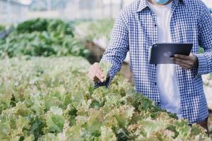 Futuristic businessman farms vegetables and crops using modern AI technology using mobile phones, temperature and humidity sensors, water tracking, climate control, holographic data data icons. photo