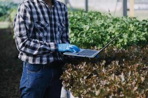 Futuristic businessman farms vegetables and crops using modern AI technology using mobile phones, temperature and humidity sensors, water tracking, climate control, holographic data data icons. photo