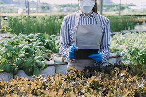 Futuristic businessman farms vegetables and crops using modern AI technology using mobile phones, temperature and humidity sensors, water tracking, climate control, holographic data data icons. photo