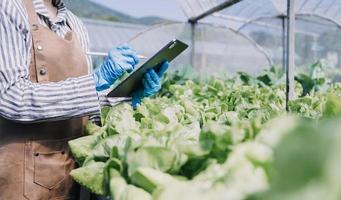 Futuristic businessman farms vegetables and crops using modern AI technology using mobile phones, temperature and humidity sensors, water tracking, climate control, holographic data data icons. photo