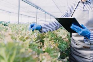 Futuristic businessman farms vegetables and crops using modern AI technology using mobile phones, temperature and humidity sensors, water tracking, climate control, holographic data data icons. photo