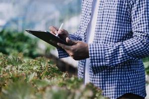 Futuristic businessman farms vegetables and crops using modern AI technology using mobile phones, temperature and humidity sensors, water tracking, climate control, holographic data data icons. photo