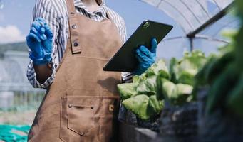 Futuristic businessman farms vegetables and crops using modern AI technology using mobile phones, temperature and humidity sensors, water tracking, climate control, holographic data data icons. photo