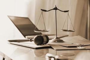 Justice and law concept.Male judge in a courtroom with the gavel, working with, computer and docking keyboard, eyeglasses, on table in morning light photo