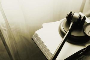 Justice and law concept.Male judge in a courtroom with the gavel, working with, computer and docking keyboard, eyeglasses, on table in morning light photo