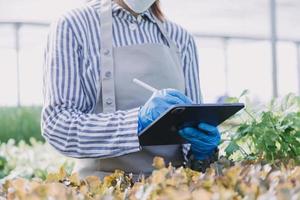 Futuristic businessman farms vegetables and crops using modern AI technology using mobile phones, temperature and humidity sensors, water tracking, climate control, holographic data data icons. photo