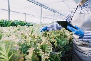 Futuristic businessman farms vegetables and crops using modern AI technology using mobile phones, temperature and humidity sensors, water tracking, climate control, holographic data data icons. photo