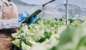 Futuristic businessman farms vegetables and crops using modern AI technology using mobile phones, temperature and humidity sensors, water tracking, climate control, holographic data data icons. photo