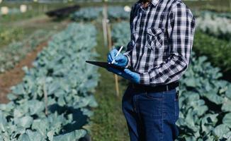 Futuristic businessman farms vegetables and crops using modern AI technology using mobile phones, temperature and humidity sensors, water tracking, climate control, holographic data data icons. photo