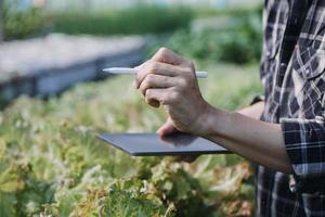 Futuristic businessman farms vegetables and crops using modern AI technology using mobile phones, temperature and humidity sensors, water tracking, climate control, holographic data data icons. photo