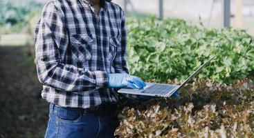 Futuristic businessman farms vegetables and crops using modern AI technology using mobile phones, temperature and humidity sensors, water tracking, climate control, holographic data data icons. photo