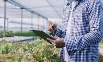 Futuristic businessman farms vegetables and crops using modern AI technology using mobile phones, temperature and humidity sensors, water tracking, climate control, holographic data data icons. photo