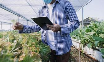 Futuristic businessman farms vegetables and crops using modern AI technology using mobile phones, temperature and humidity sensors, water tracking, climate control, holographic data data icons. photo