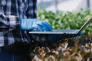 Futuristic businessman farms vegetables and crops using modern AI technology using mobile phones, temperature and humidity sensors, water tracking, climate control, holographic data data icons. photo