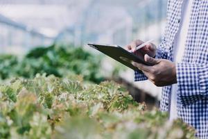 Futuristic businessman farms vegetables and crops using modern AI technology using mobile phones, temperature and humidity sensors, water tracking, climate control, holographic data data icons. photo