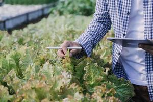 Futuristic businessman farms vegetables and crops using modern AI technology using mobile phones, temperature and humidity sensors, water tracking, climate control, holographic data data icons. photo