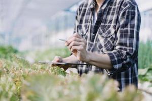 Futuristic businessman farms vegetables and crops using modern AI technology using mobile phones, temperature and humidity sensors, water tracking, climate control, holographic data data icons. photo