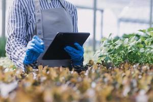 Futuristic businessman farms vegetables and crops using modern AI technology using mobile phones, temperature and humidity sensors, water tracking, climate control, holographic data data icons. photo