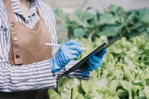 Futuristic businessman farms vegetables and crops using modern AI technology using mobile phones, temperature and humidity sensors, water tracking, climate control, holographic data data icons. photo