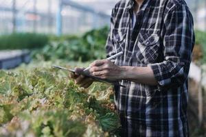 Futuristic businessman farms vegetables and crops using modern AI technology using mobile phones, temperature and humidity sensors, water tracking, climate control, holographic data data icons. photo