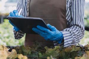 Futuristic businessman farms vegetables and crops using modern AI technology using mobile phones, temperature and humidity sensors, water tracking, climate control, holographic data data icons. photo