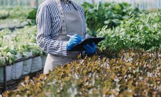 Futuristic businessman farms vegetables and crops using modern AI technology using mobile phones, temperature and humidity sensors, water tracking, climate control, holographic data data icons. photo