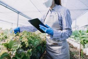 Futuristic businessman farms vegetables and crops using modern AI technology using mobile phones, temperature and humidity sensors, water tracking, climate control, holographic data data icons. photo