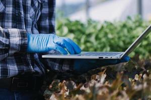 Futuristic businessman farms vegetables and crops using modern AI technology using mobile phones, temperature and humidity sensors, water tracking, climate control, holographic data data icons. photo