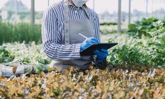 Futuristic businessman farms vegetables and crops using modern AI technology using mobile phones, temperature and humidity sensors, water tracking, climate control, holographic data data icons. photo