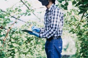 Futuristic businessman farms vegetables and crops using modern AI technology using mobile phones, temperature and humidity sensors, water tracking, climate control, holographic data data icons. photo