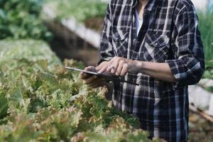 Futuristic businessman farms vegetables and crops using modern AI technology using mobile phones, temperature and humidity sensors, water tracking, climate control, holographic data data icons. photo