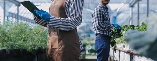 un hombre de negocios futurista cultiva verduras y cultivos usando tecnología moderna de inteligencia artificial usando teléfonos móviles, sensores de temperatura y humedad, rastreo de agua, control climático, íconos de datos holográficos. foto