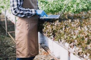 Futuristic businessman farms vegetables and crops using modern AI technology using mobile phones, temperature and humidity sensors, water tracking, climate control, holographic data data icons. photo