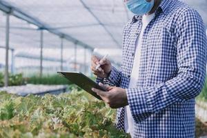 Futuristic businessman farms vegetables and crops using modern AI technology using mobile phones, temperature and humidity sensors, water tracking, climate control, holographic data data icons. photo