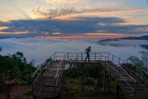 Man traveler enjoying mist viewpoint on the mountain at Nong Khai province, Thailand photo