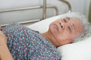 Asian elder senior woman patient holding bed rail while lie down with hope waiting her family in hospital. photo