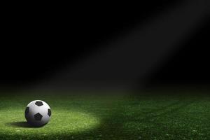 a ball for soccer is being illuminated in the middle of a dark field photo