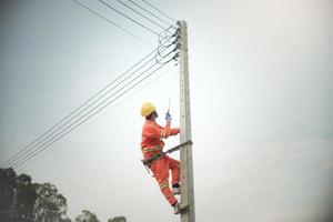 instalador de cables que trabaja desde escalar el poste de la luz en el cableado de distribución de cables foto