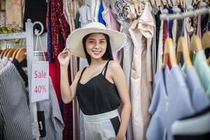 retrato de una mujer joven. pruébate vestidos y sombreros. en la tienda de ropa foto