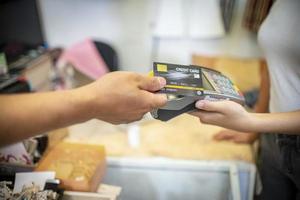 Hand of customer paying with contactless credit card with NFC technology. Bartender with a credit card reader machine at bar counter with female holding credit card. Focus on hands. photo