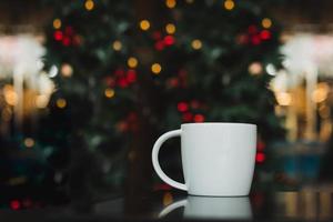 taza de café en la mesa con luz navideña en el fondo. foto