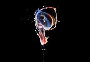 Falling drops of colored liquid, splashes on a black background, motion blur photo