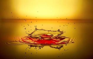 splash of red liquid with reflection and drops on a yellow background photo