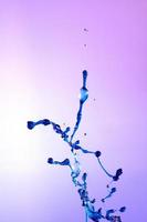 abstract purple background of blue water splash, collision of colored drops. photo