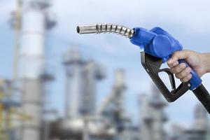 Holding a fuel nozzle against with Oil refinery blurred background photo