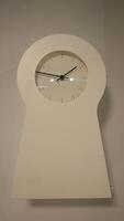 Unique white wall clock shaped like a keyhole. photo