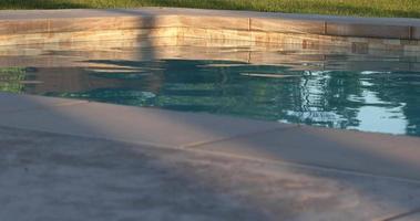 Agua tranquila de la piscina y terraza al sol de la tarde. video