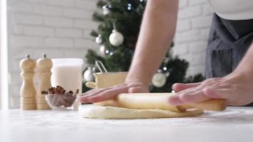 Chef cutting cinnamon rolls, christmas tree with lights on the background video
